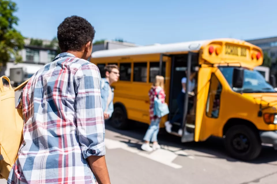 Children walking toward yellow school bus on a sunny day.